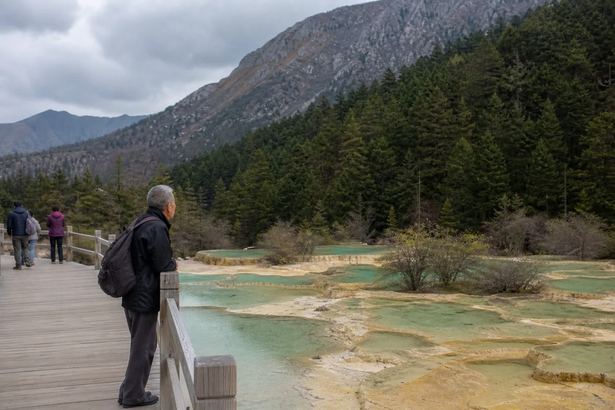Visitors walking beside natural travertine pools at Huanglong in Sichuan