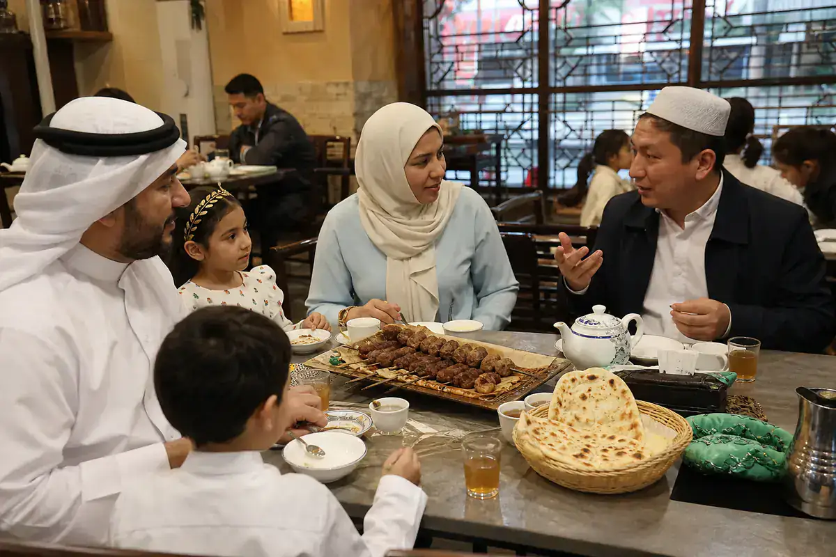 Gulf Muslim family sharing an Eid dinner with a Chinese Muslim guide