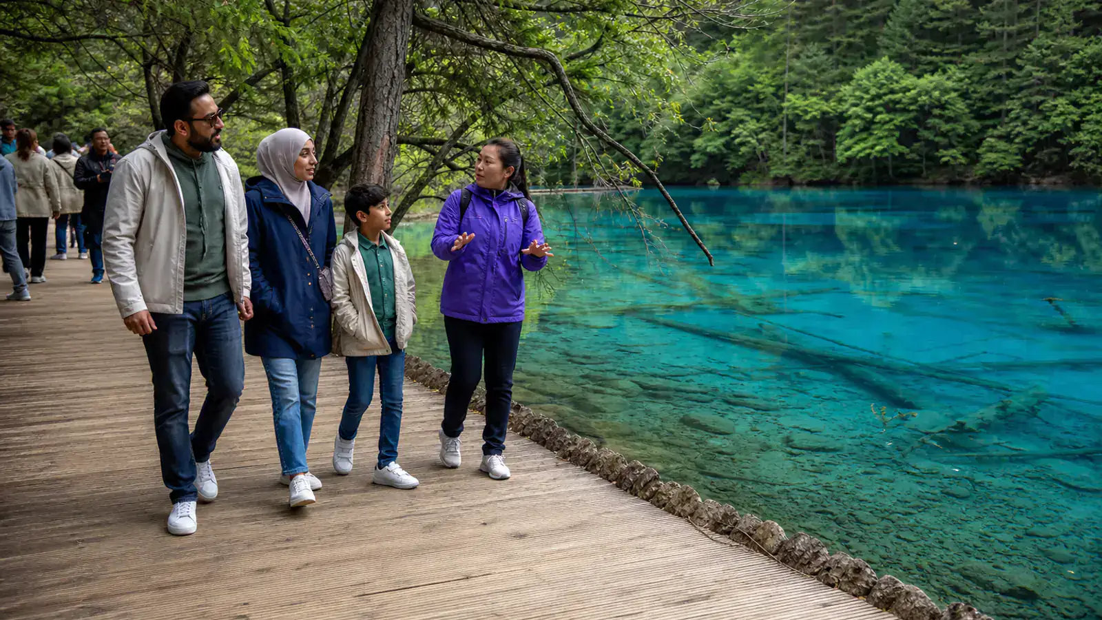 Gulf family walking beside a blue Jiuzhaigou lake in summer
