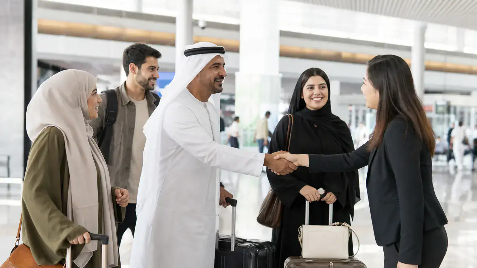 Group of UAE travelers meeting a coordinator in a Chinese airport arrivals hall