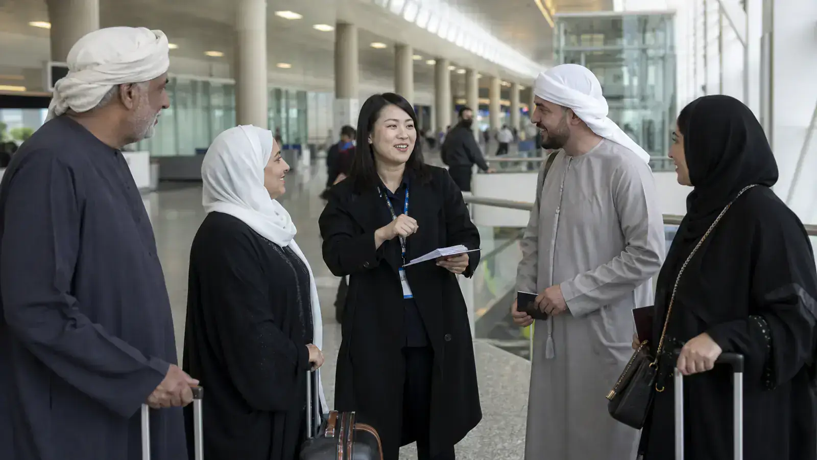 Travelers from Gulf countries meeting a coordinator in a Chinese airport arrivals hall