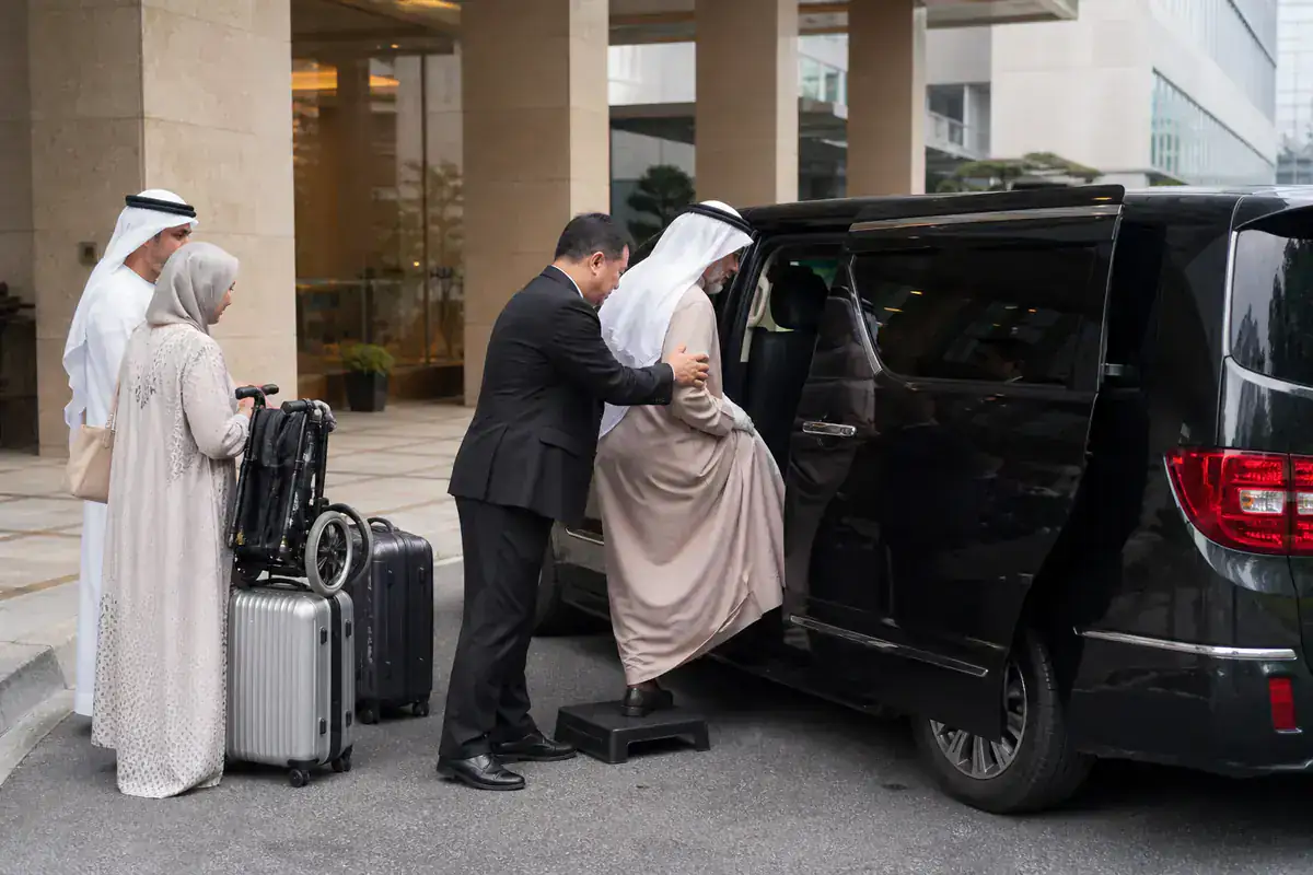 Chauffeur helping an older Gulf traveler board an accessible executive MPV
