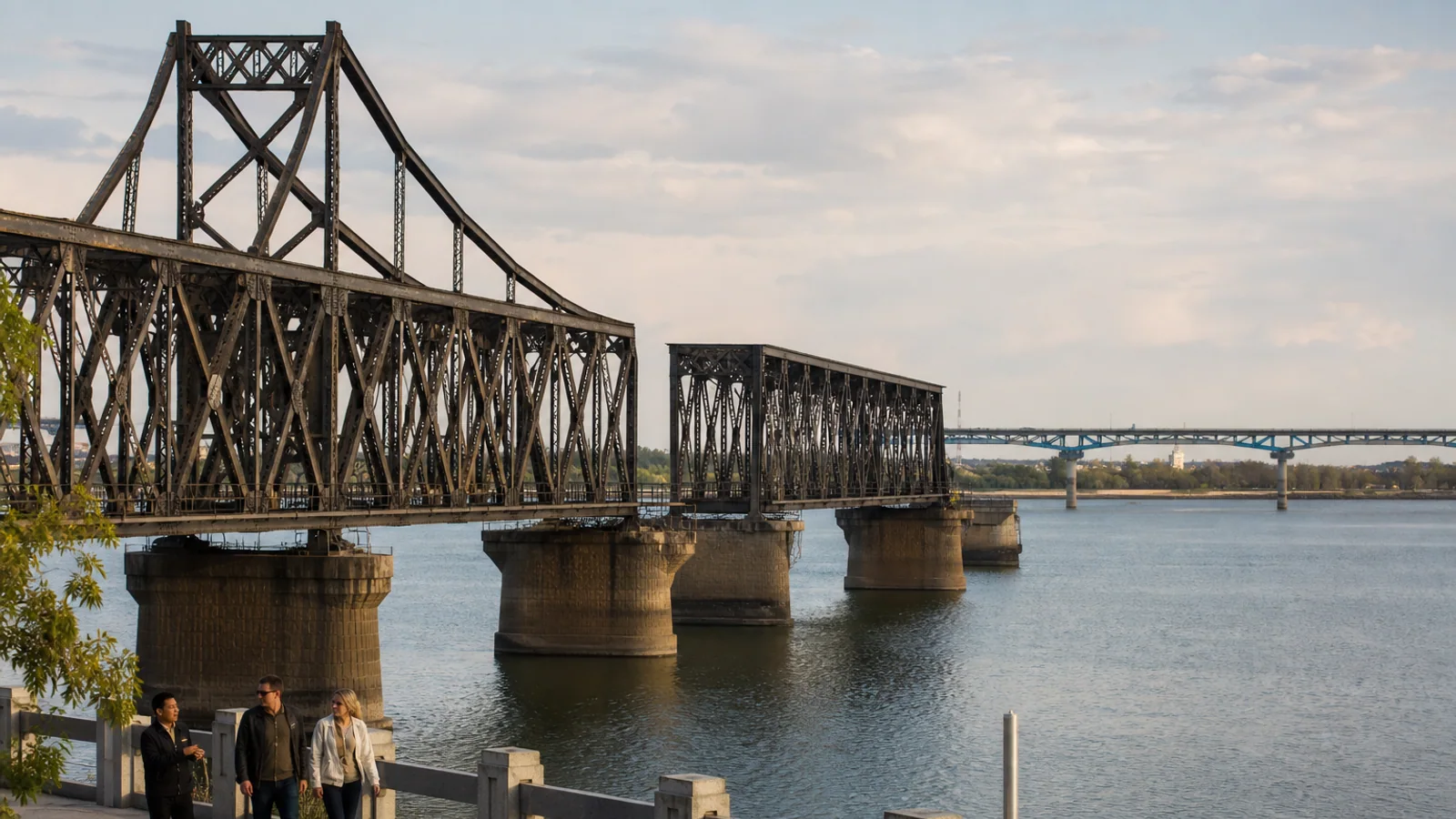 International travelers walking beside the Yalu River Broken Bridge in Dandong with a local guide