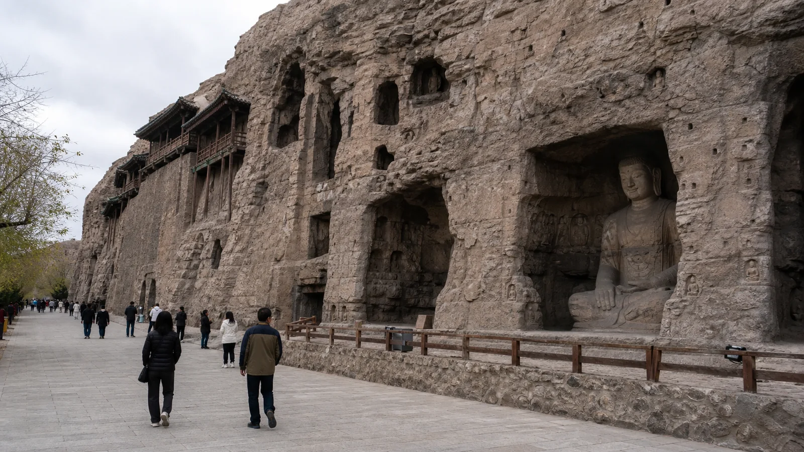 Visitors walking beside the carved cliff and Buddhist caves at Yungang Grottoes