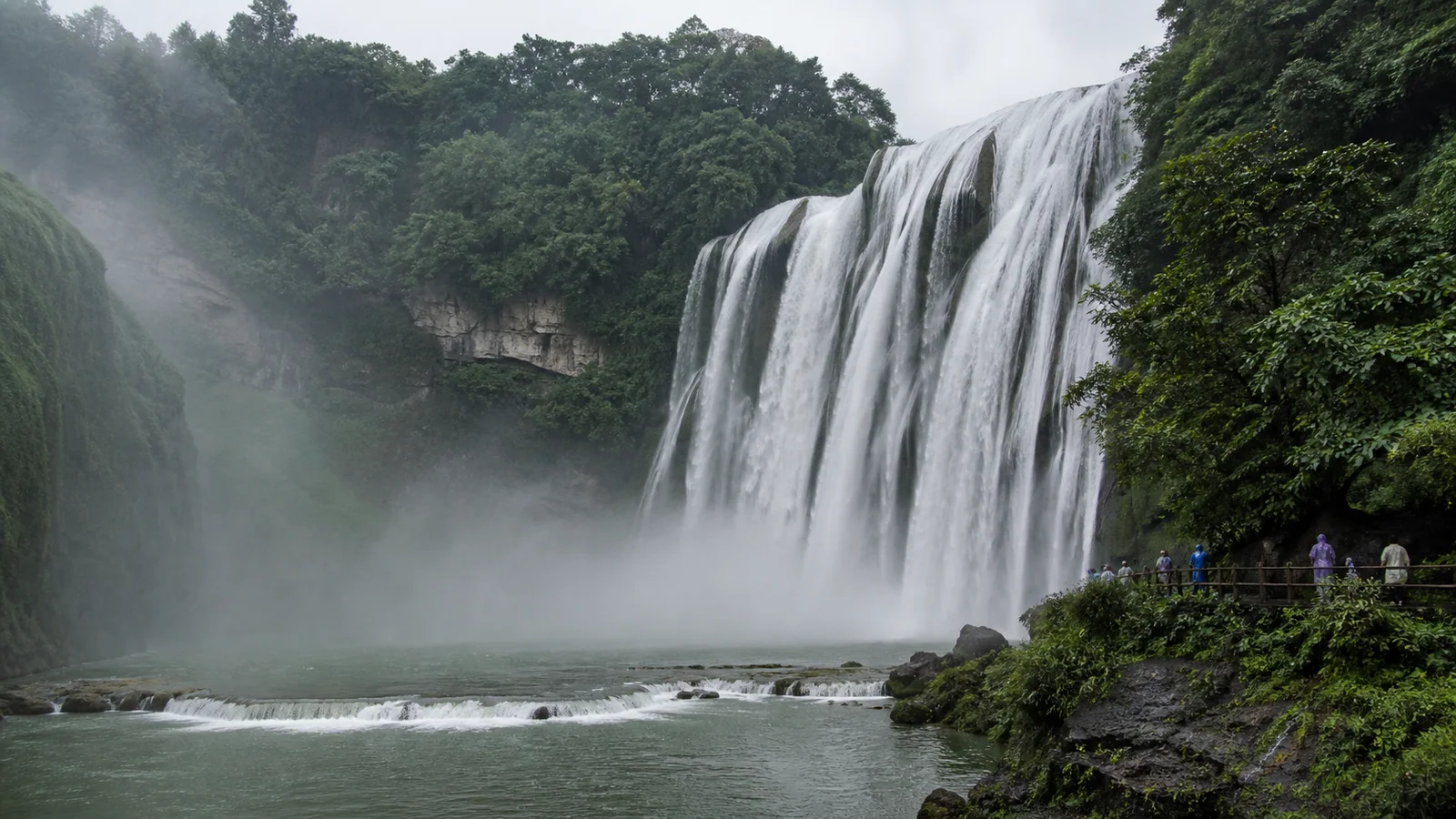 Huangguoshu Waterfall in full flow with visitors on the viewing path