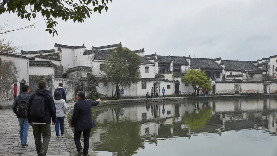 International travelers and guide beside Moon Pond in Hongcun village