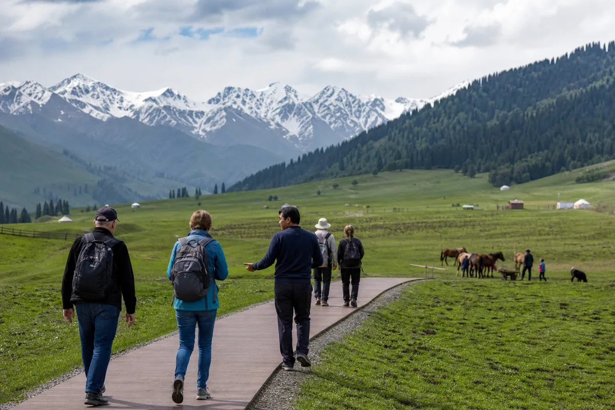 Travelers walking with a guide through Nalati grassland in the Ili Valley
