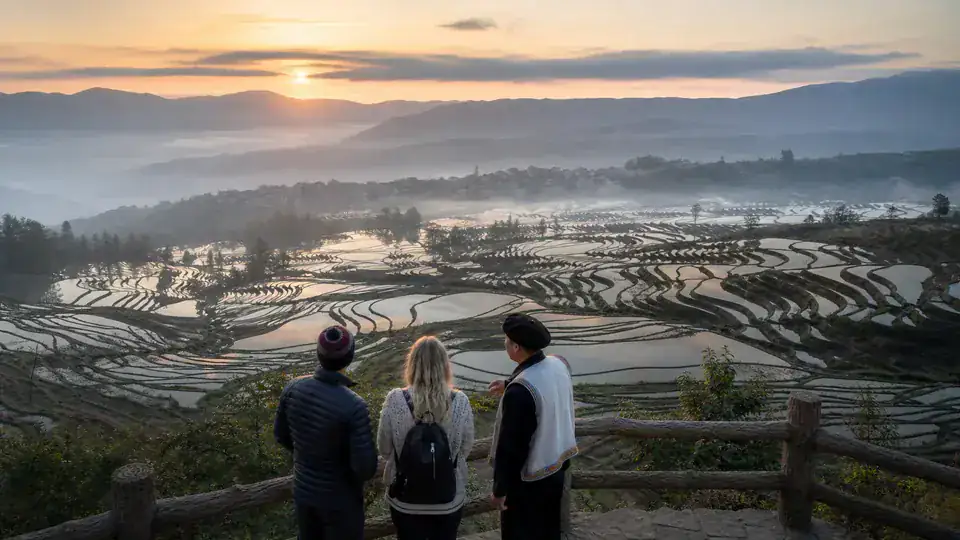 Travelers overlooking the water filled Yuanyang rice terraces at sunrise in Yunnan