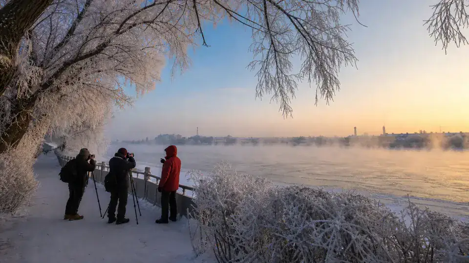 International travelers photographing rime beside the Songhua River in Jilin City at sunrise