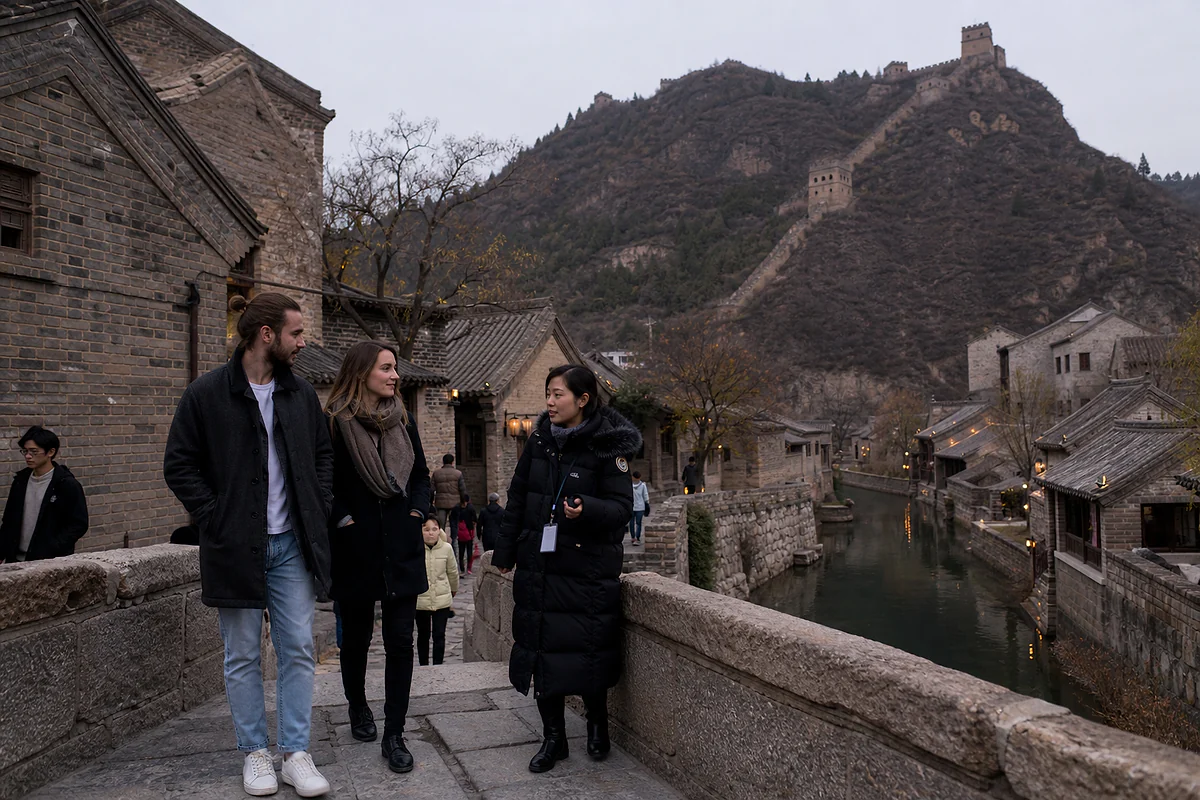 International visitors crossing a stone bridge in Gubei Water Town with Simatai Great Wall above