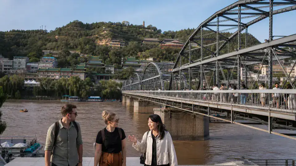 International travelers and local guide beside Zhongshan Bridge on the Yellow River in Lanzhou