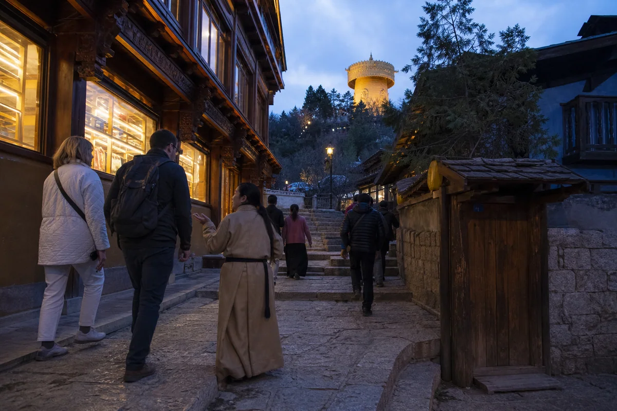 International travelers walking with a guide through Dukezong Ancient Town at blue hour