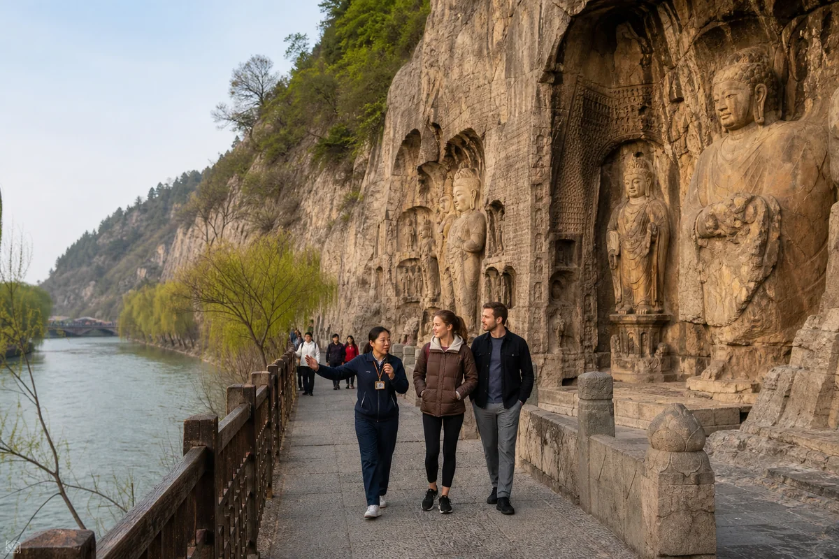 International travelers walking with a guide beside the Longmen Grottoes in spring
