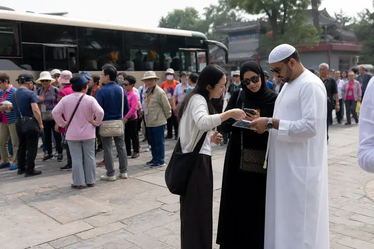 Gulf couple comparing a private plan while a tour group gathers nearby
