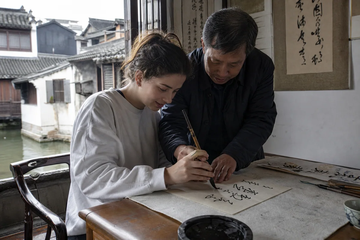 Traveler learning Chinese calligraphy in a waterside Shaoxing house