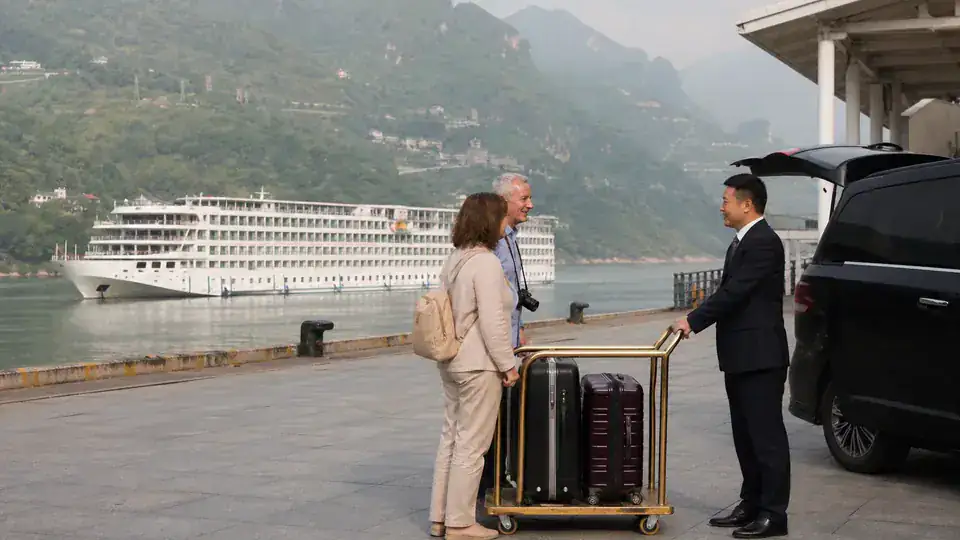 International cruise travelers meeting a private chauffeur beside a Yichang river terminal