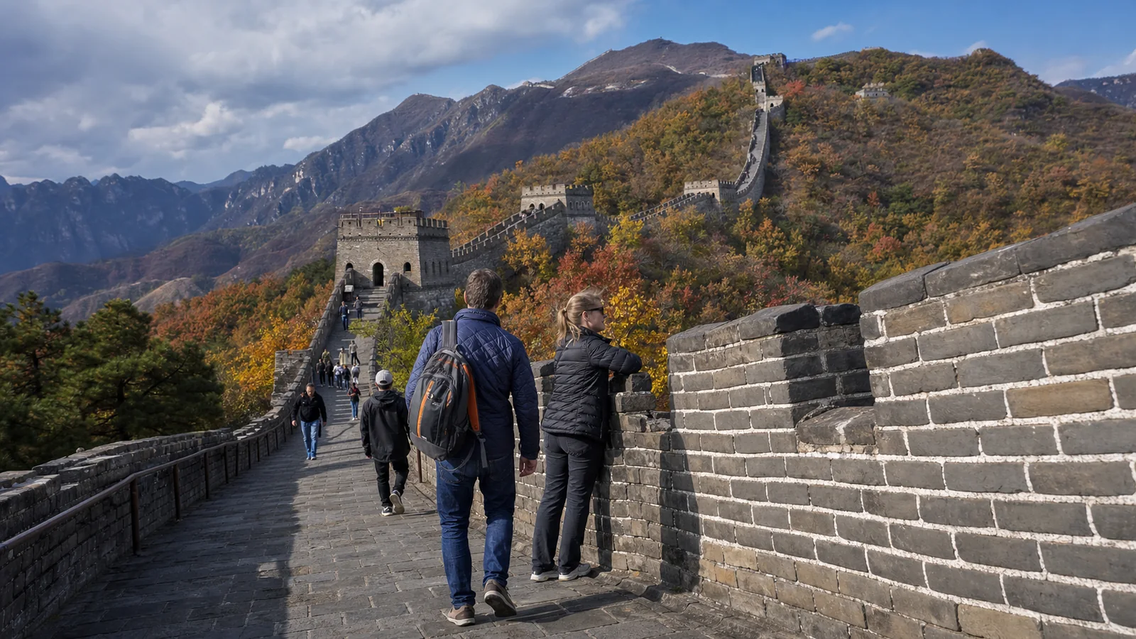 Travelers walking candidly on the Great Wall among autumn mountains and mixed crowds