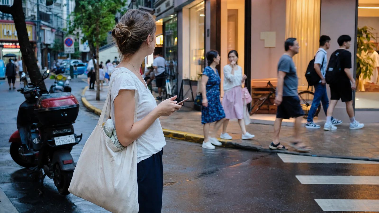 International traveler using a phone on a wet and busy Shanghai neighborhood street