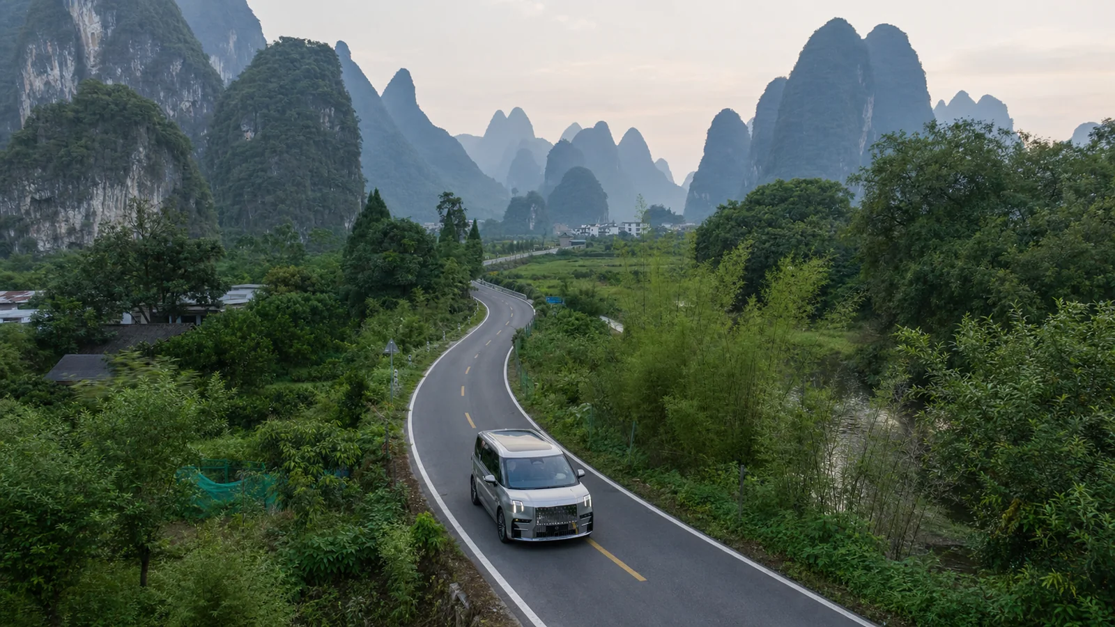 Silver ZEEKR 009 on a winding road through Guilin's karst landscape