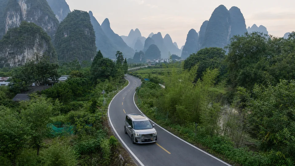 Silver ZEEKR 009 on a winding road through Guilin's karst landscape