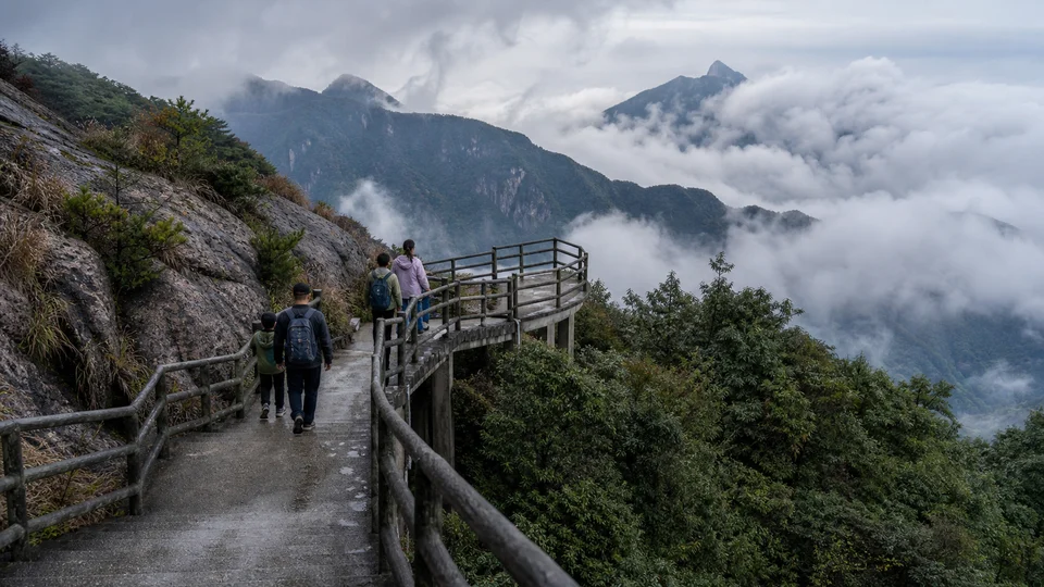Family walking on a broad cliff path above cloud at Mangshan Wuzhifeng