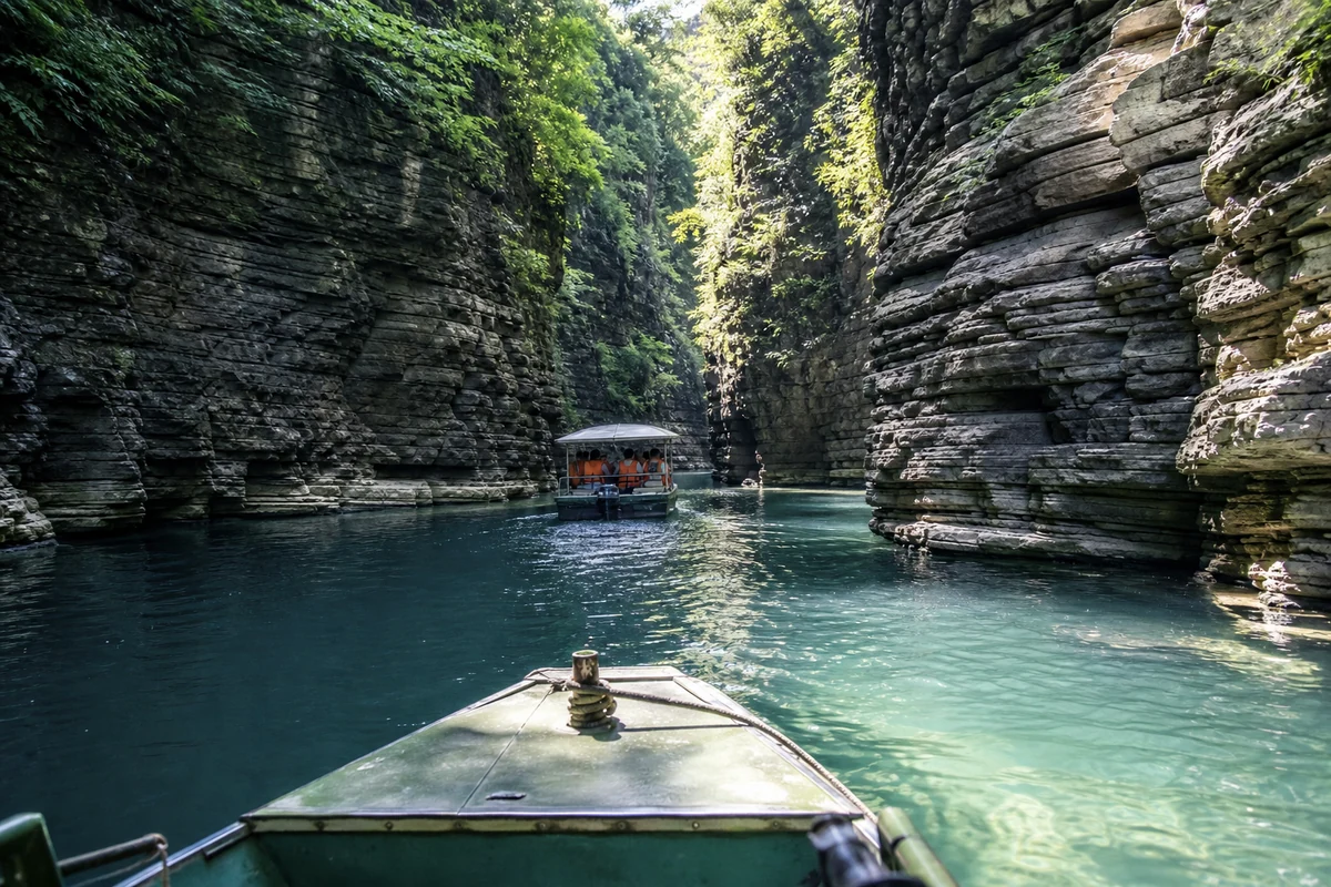 Passenger view from a sightseeing boat moving between layered limestone walls in Pingshan Canyon