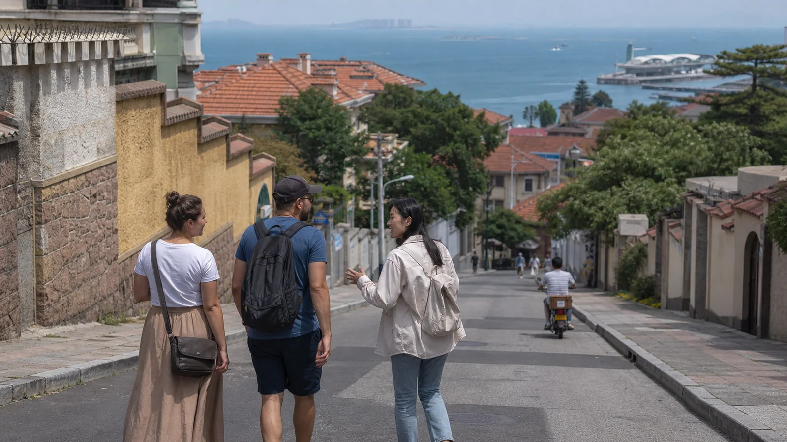 International travelers walking through Qingdao old city with a local guide and the sea ahead