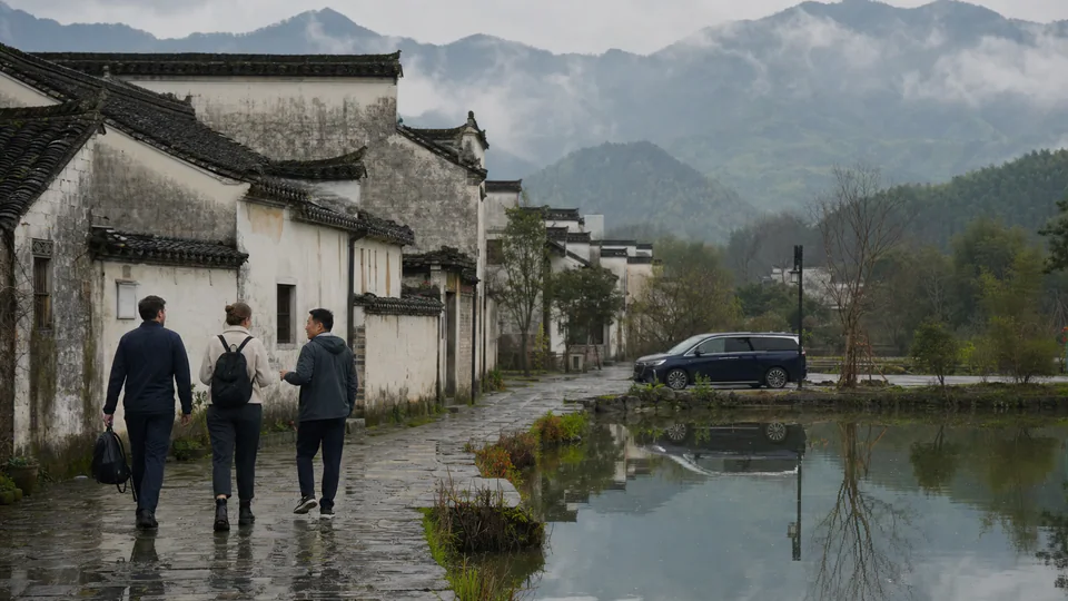 Travelers walking through a traditional Huizhou village near Huangshan on a rainy morning